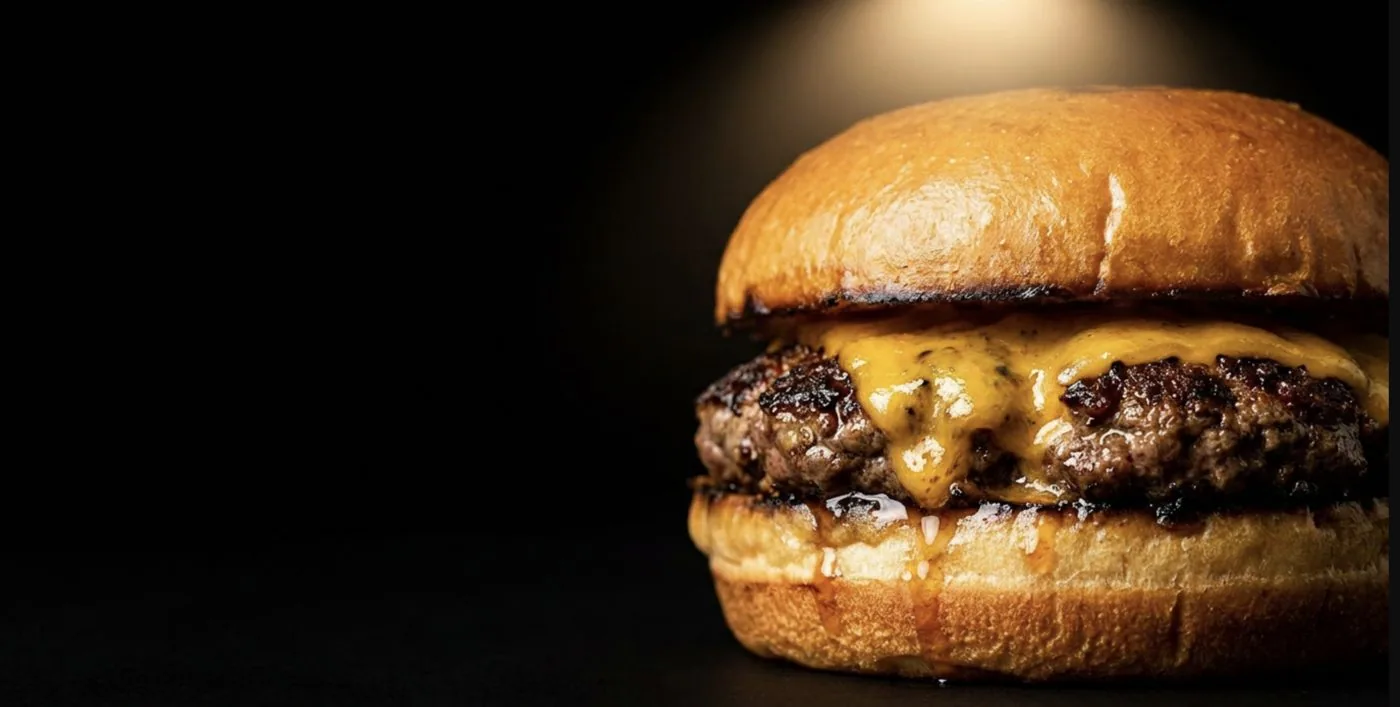 Hamburguesa BDP con cheddar fundido sobre fondo oscuro